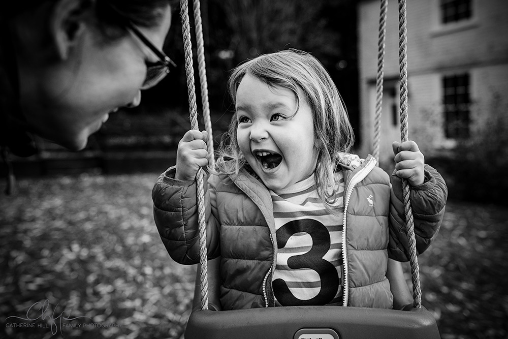family life in pictures - lyla has an excited, expressive face on her swing
